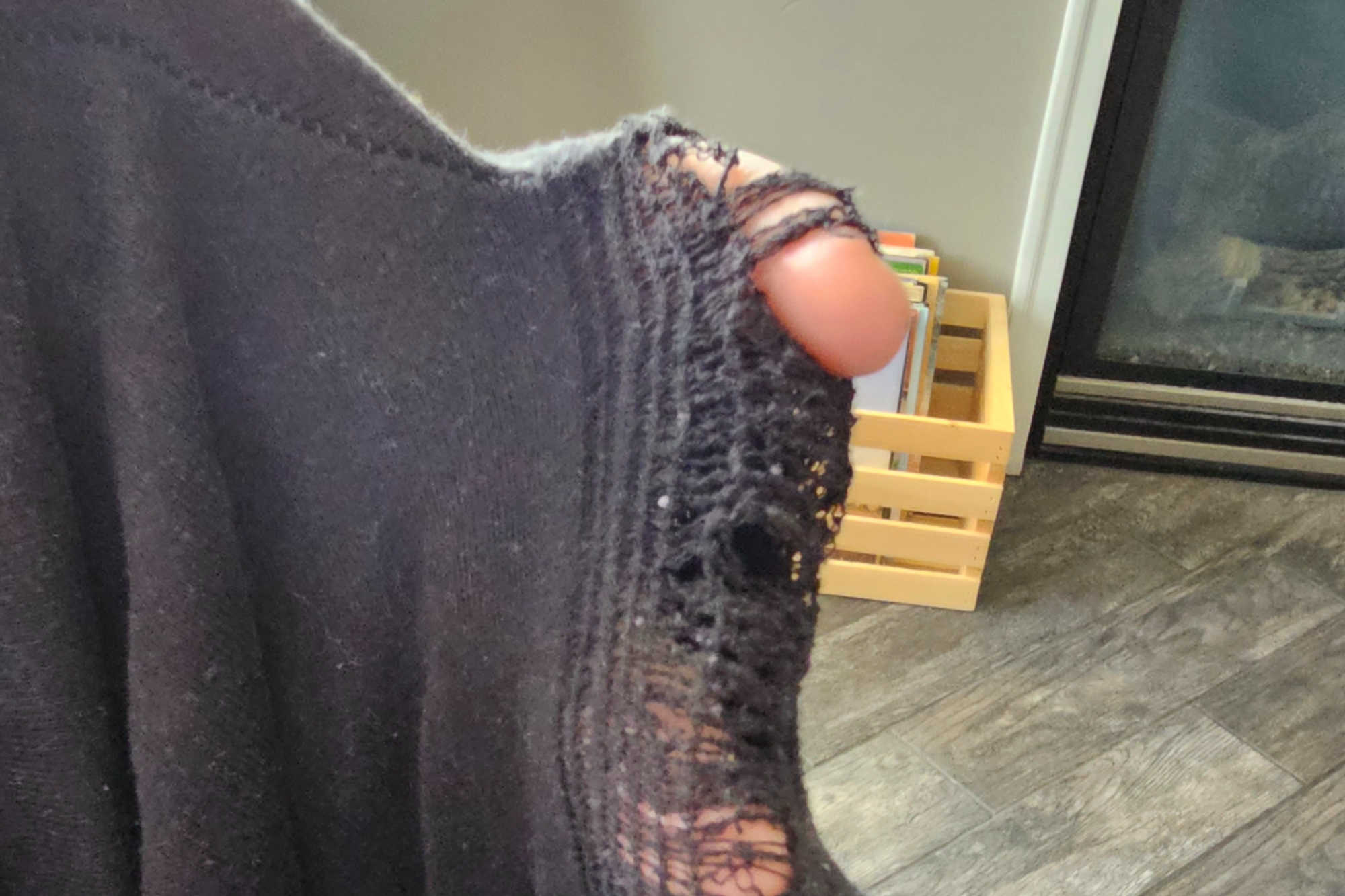 A finger poking through a hole in a pair of threadbare pants. These pants will need to be thrown out rather than donated.